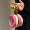 Une main tient un ensemble d'attaches en silicone colorées et flexibles pour manteaux et chapeaux.