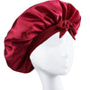 A deep red silky satin sleep bonnet tied in a bow displayed on a white mannequin head.