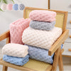 A stack of pink, gray, and light blue thickened microfiber bath towels displayed on a wooden rack.