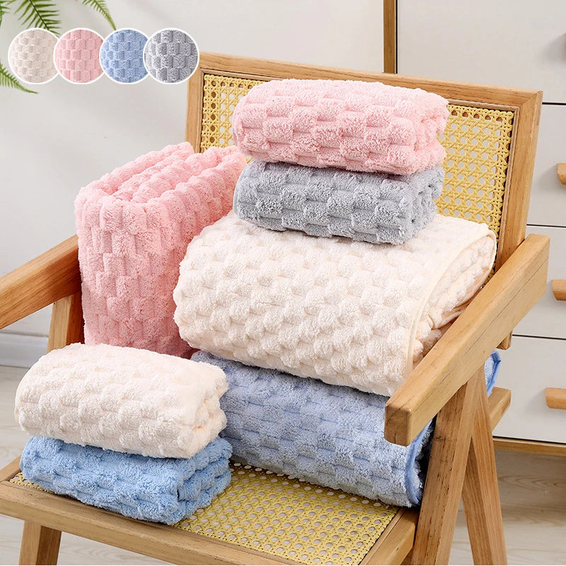 A stack of pink, gray, and light blue thickened microfiber bath towels displayed on a wooden rack.