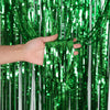 Eine Hand hält grüne metallische Tinsel-Flimmernvorhänge, die glänzende vertikale Stränge zeigen.