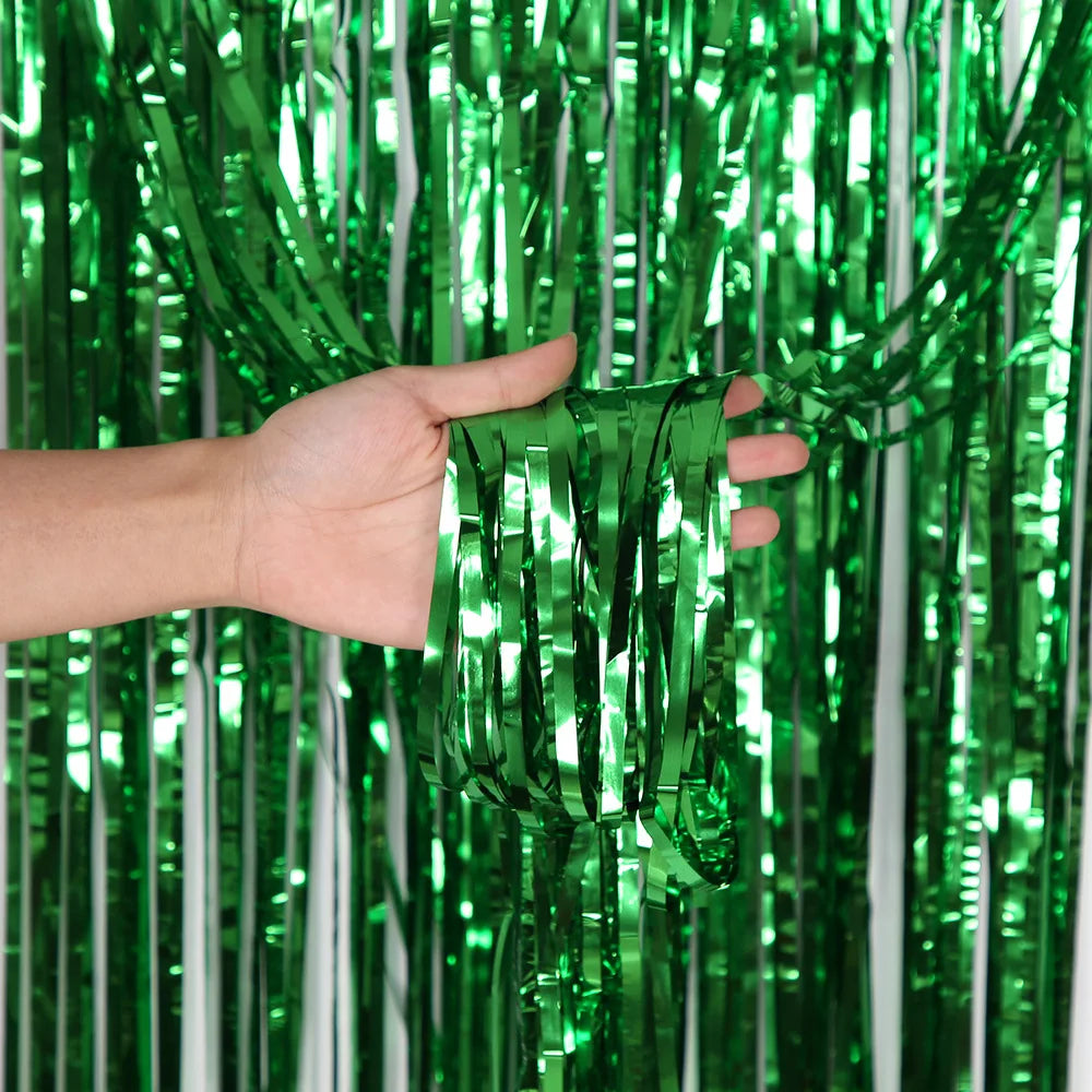 Eine Hand hält grüne metallische Tinsel-Flimmernvorhänge, die glänzende vertikale Stränge zeigen.
