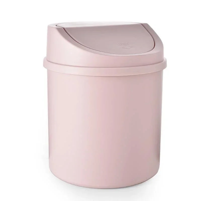 A compact desktop trash can in a dusty rose color with a flip-top lid.