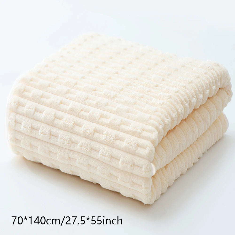 A stack of thick, cream-colored terry cloth bath towels folded neatly on a white surface.