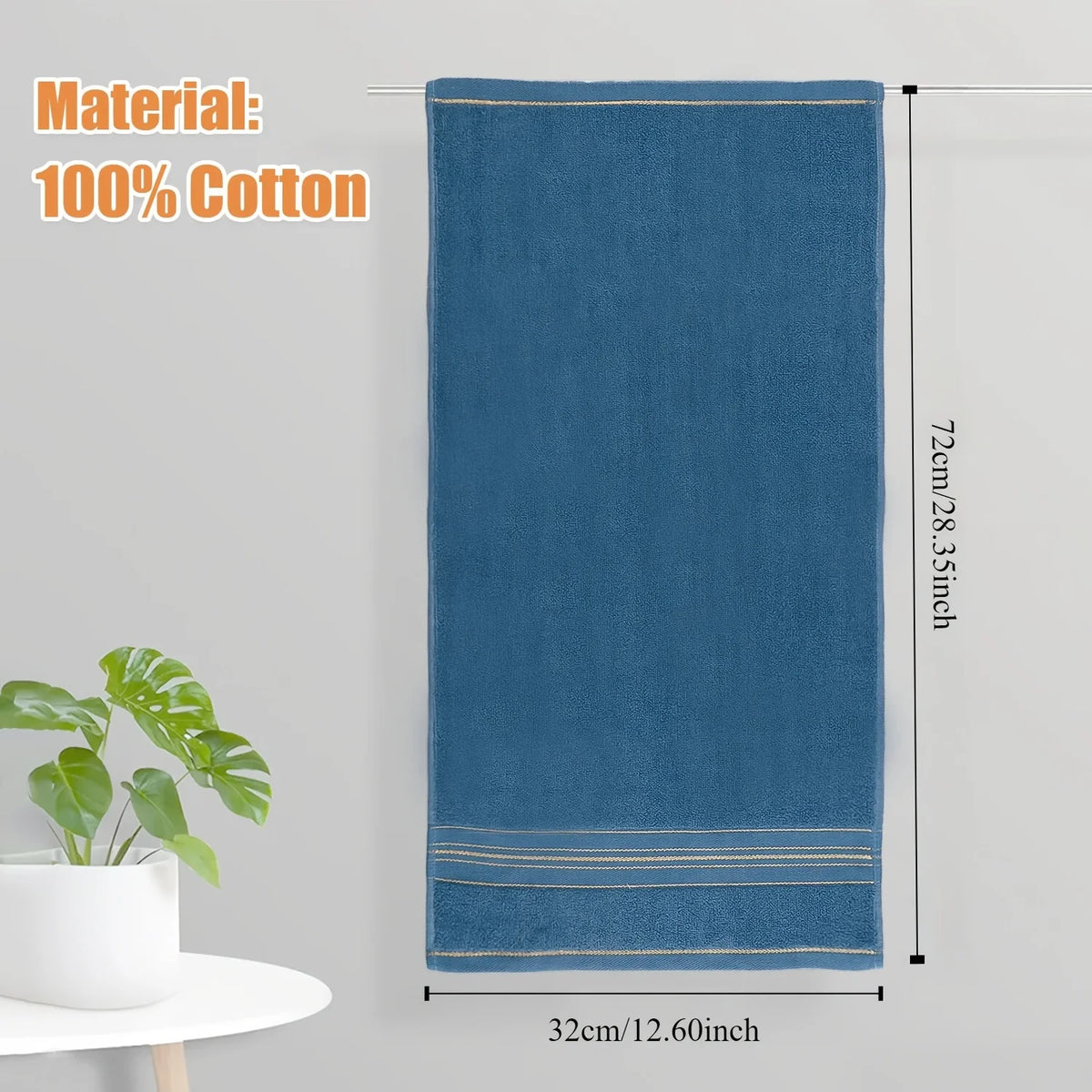 A dark blue 100% cotton bath towel hanging vertically against a light gray wall.