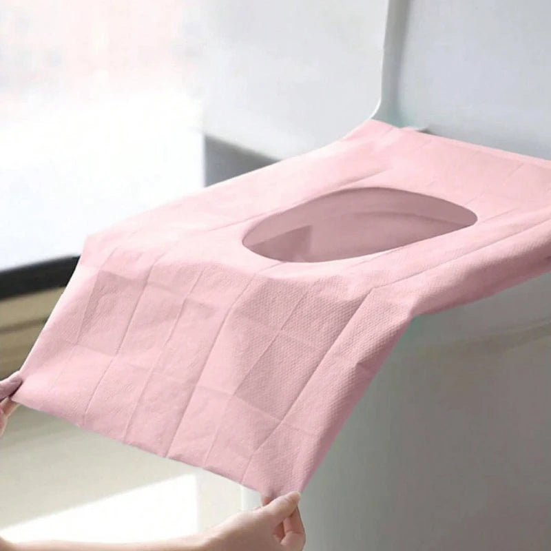 Pinker Einweg-Toilettenhalsschutz wird auf eine Toilettensitz gelegt.