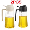 Two clear glass oil spray bottles with black and white tops containing yellow cooking oil.
