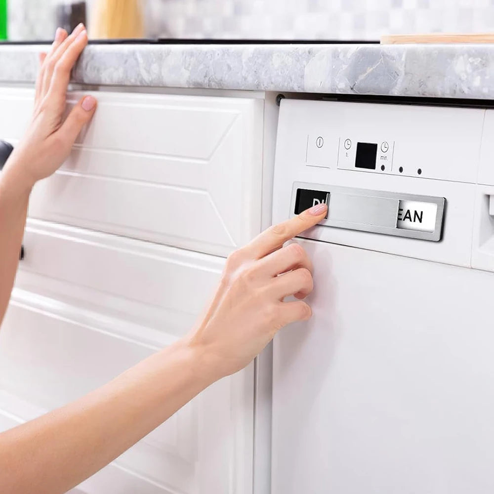 A hand is placing a dishwasher magnet onto the door of a white appliance.