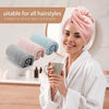 A woman wearing a pink microfiber hair towel wrap holds a mug in a bathroom setting.