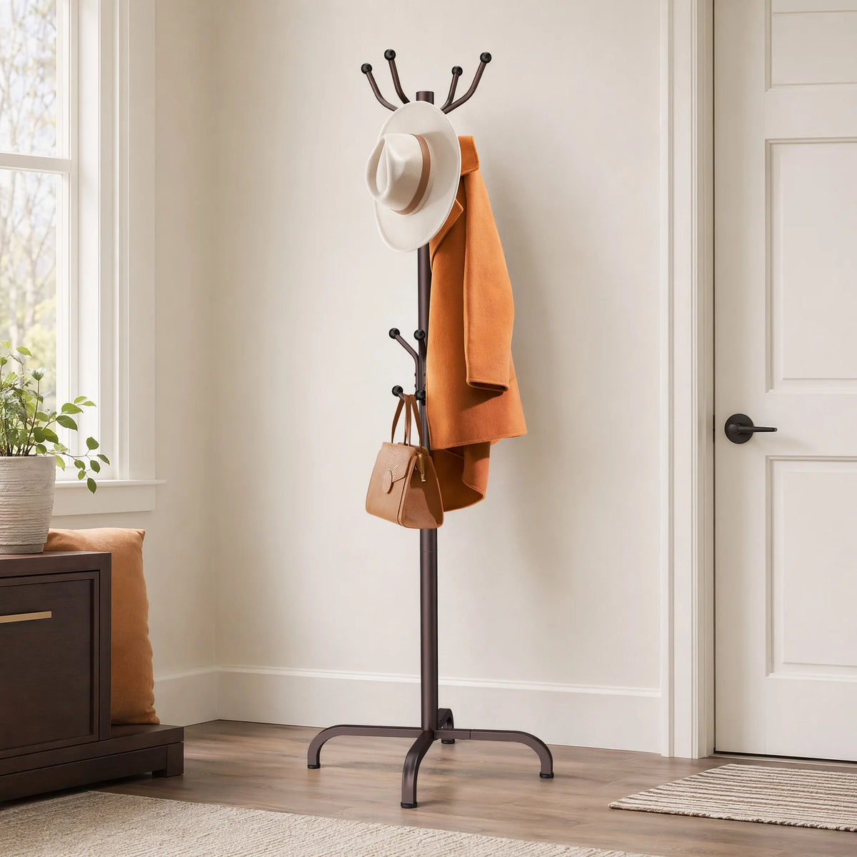 A freestanding metal coat rack with fourteen hooks displaying a tan coat and a brown leather bag.