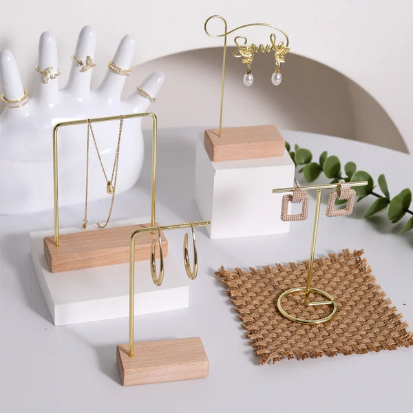 A wooden jewelry display rack featuring gold-toned stands for earrings and necklaces, set against a white background.
