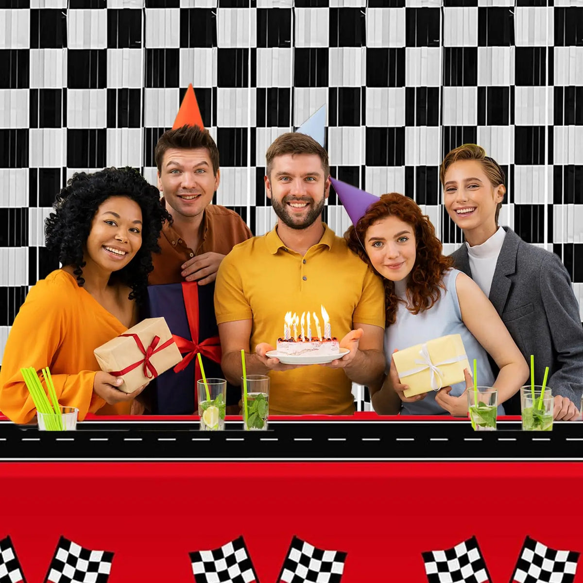 A family of four celebrating with birthday candles in front of a black and white checkered foil curtain backdrop.