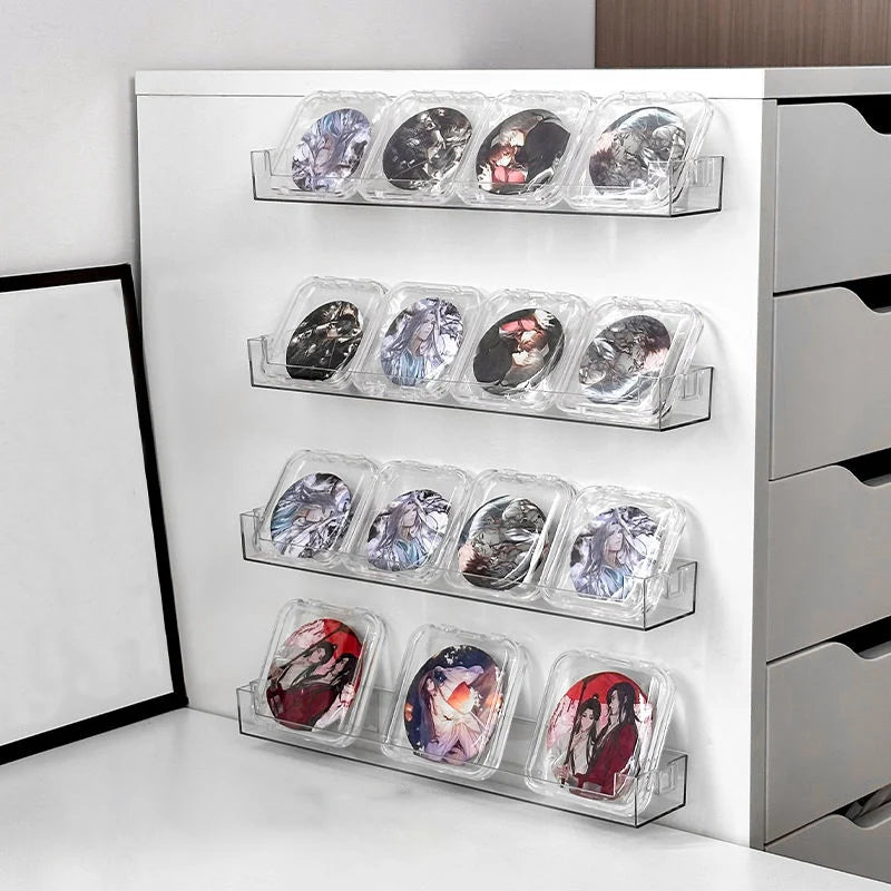 A white wall mounted acrylic display shelf holding multiple clear plastic cases of collectible items.