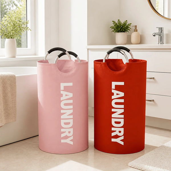 A pair of orange and pink fabric laundry hampers with black handles sitting on a light floor.