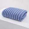 A rolled light blue thickened microfiber bath towel resting on a white surface.