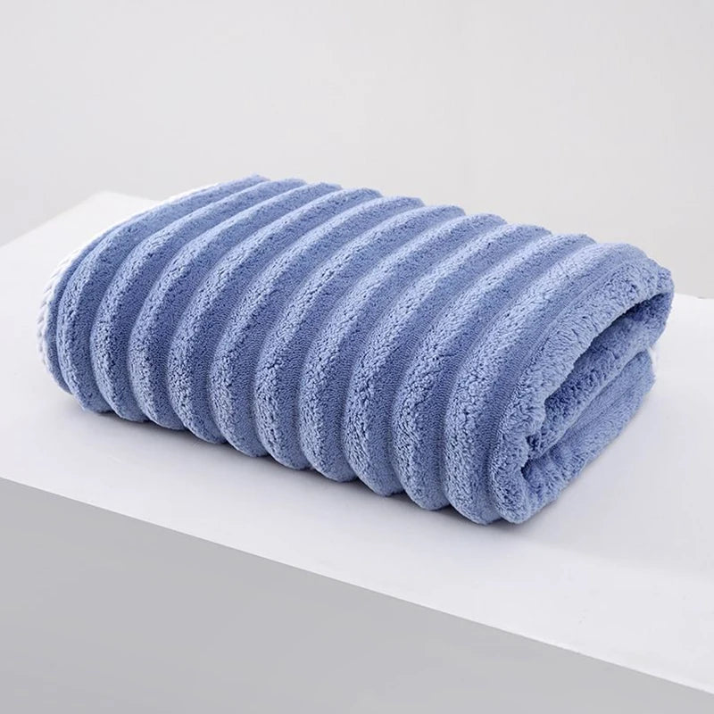 A rolled light blue thickened microfiber bath towel resting on a white surface.