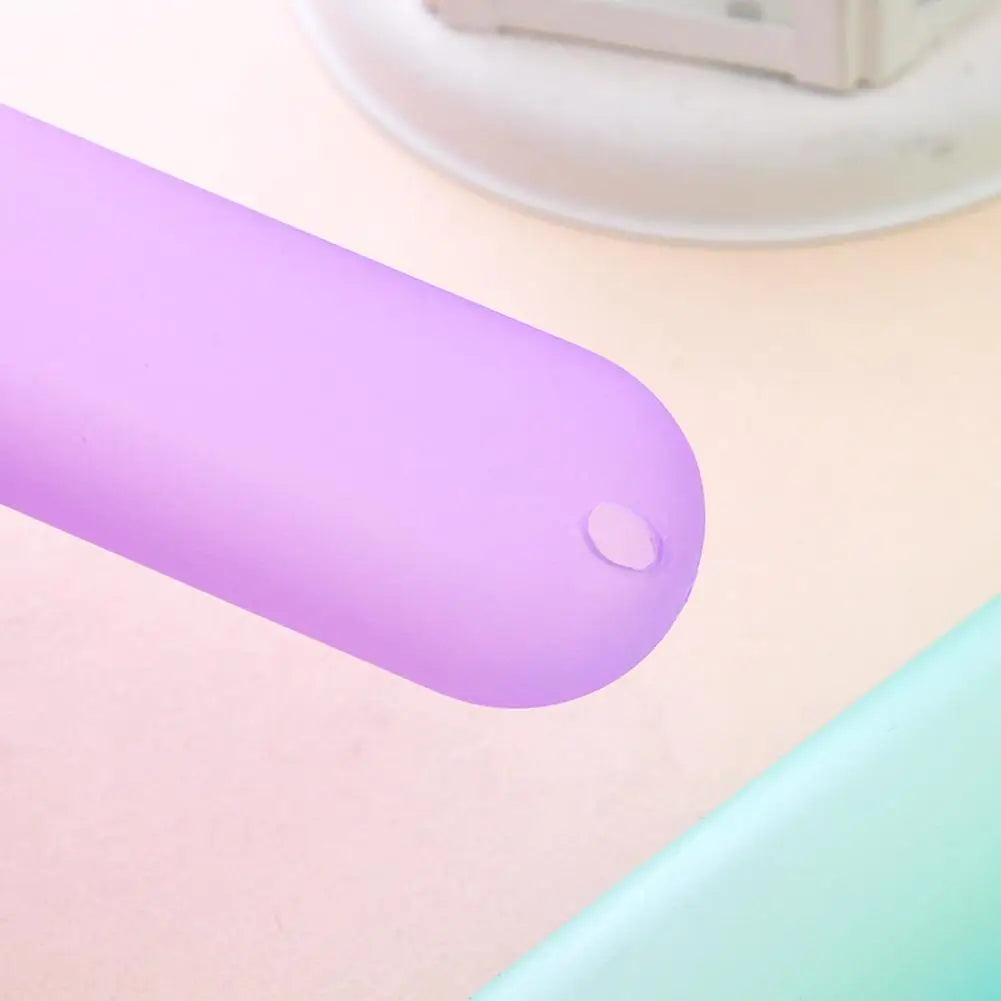 A purple portable toothbrush storage case with a smooth, elongated body is shown on a light pink surface.