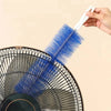 A hand holds a blue cleaning brush with a white handle, positioned against a black fan grille.