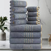 A stack of three gray bath towels with gold stripes on a white marble surface.