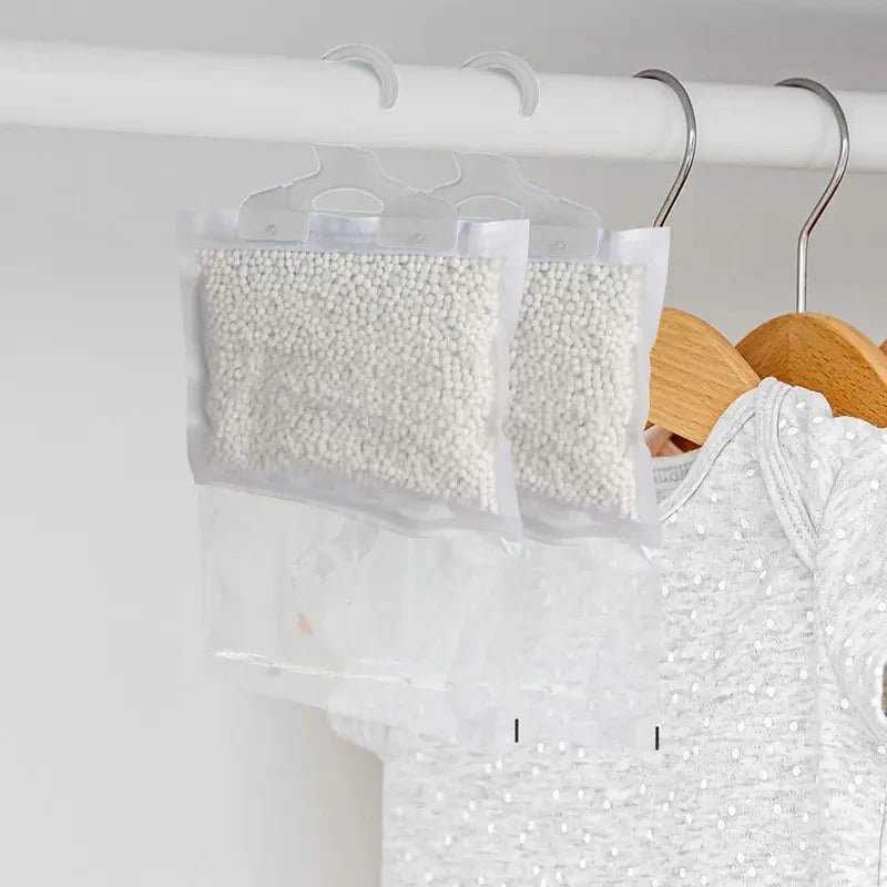 Clear reusable moisture absorber bags with hooks hanging on a white rack