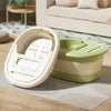 A white portable foldable foot bath tub is shown resting on a light-colored mat next to a green storage container.