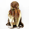 A women's square paisley print scarf in gold and brown tones tied around a dark brown ponytail.