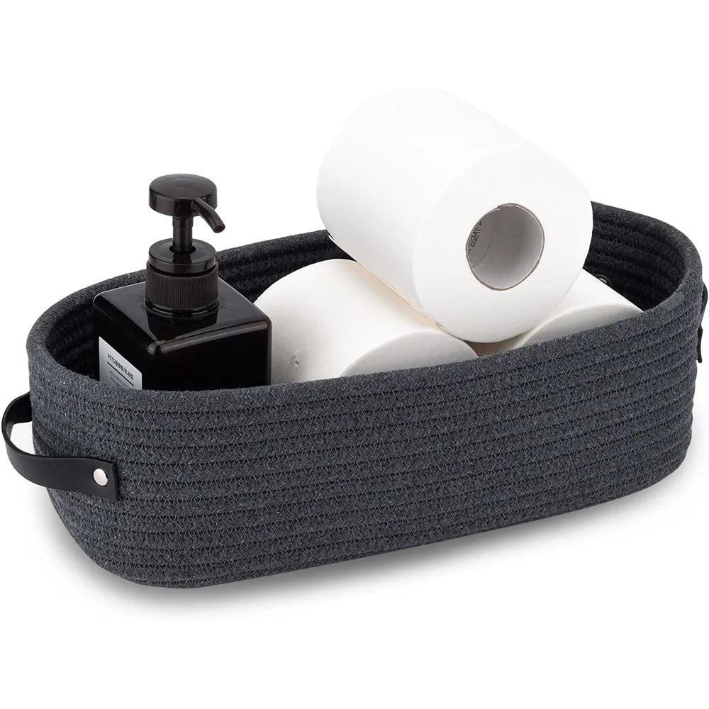 A dark gray woven cotton storage basket filled with white toilet paper rolls and a black dispenser.