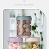 Two glass meal prep jars with airtight lids, one containing pink candies and the other containing dried vegetables.