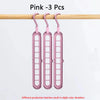 Three pink space-saving clothes organizer hangers hanging on a wooden rod.