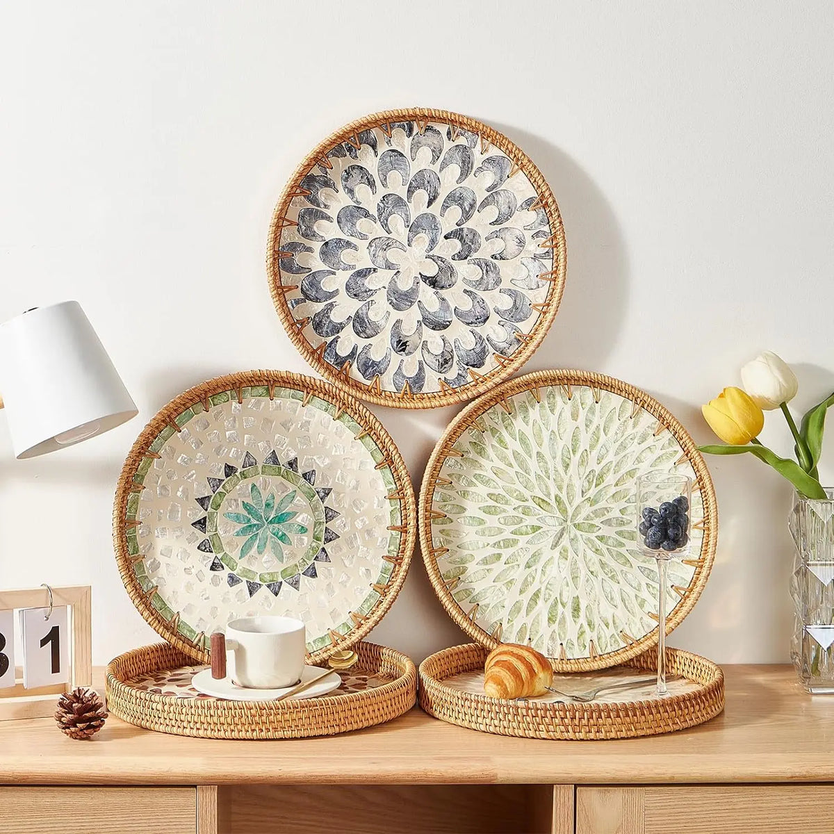 Round rattan serving tray with mother of pearl inlay featuring a white cup and a small pastry.