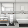 Weiβes Badezimmer mit Toilette, Waschbereich und Badewanne mit schwarzen Memory-Foam-Bodenmatten.