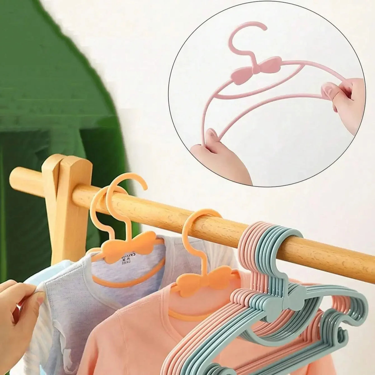 A close-up of reusable plastic clothes hangers for kids and nursery, showing various colors and a detail of the hanger design