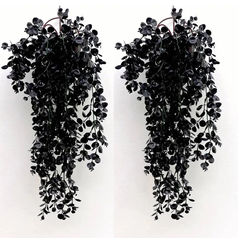 A pair of black artificial flower garlands with dark green leaves and thin stems hanging down.