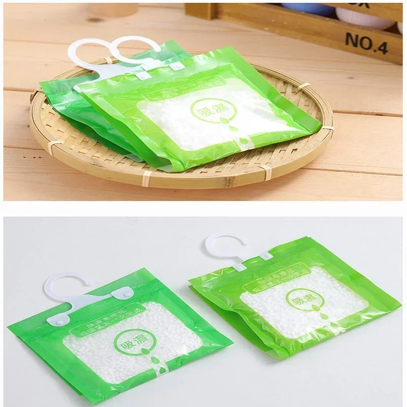 Two green hanging bags filled with white moisture absorber material are displayed on a wooden tray.