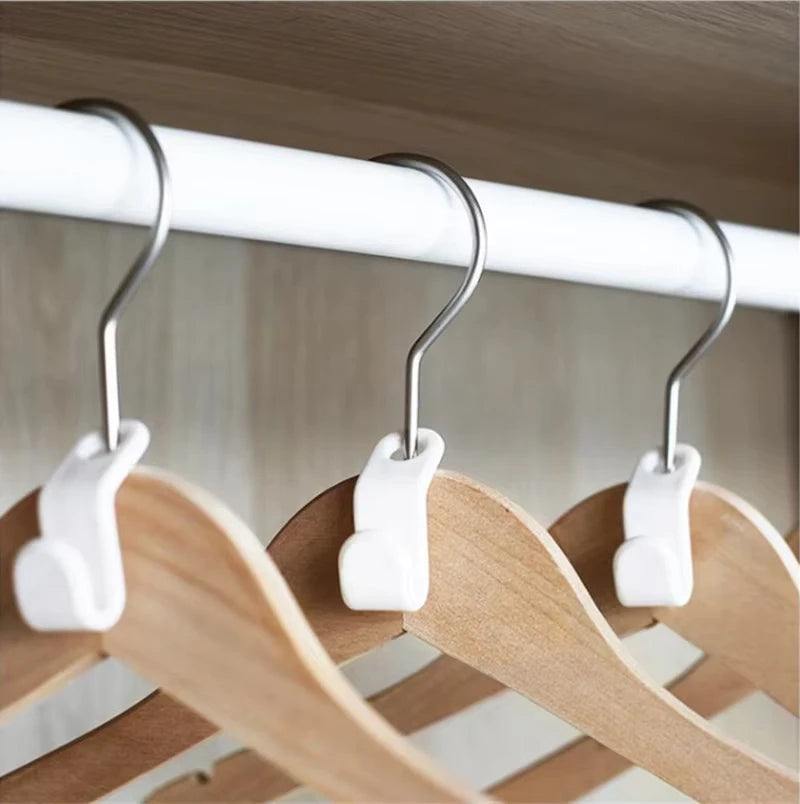 Drei weiße Kleiderbügel hängen von einem Holzstab in einer Kleiderschrank-Organisation.