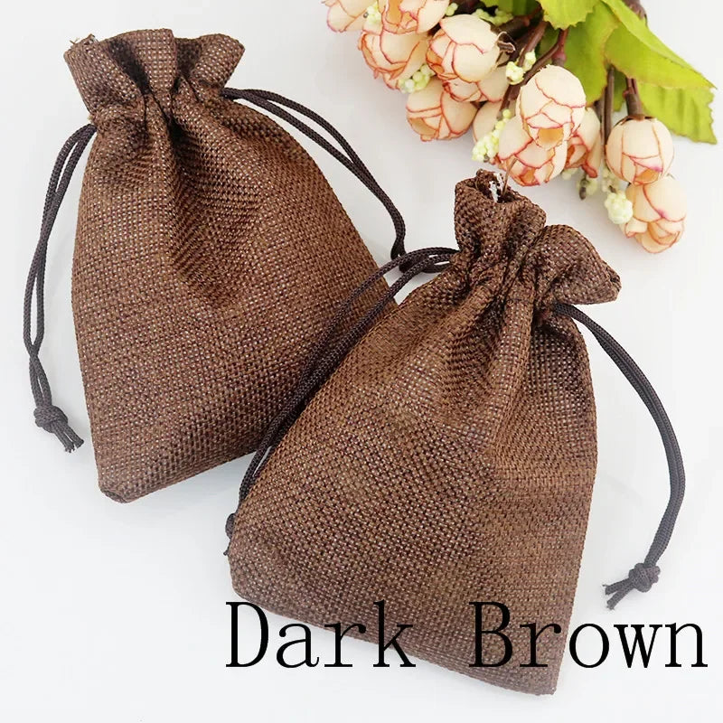 Dunkelbraune Jute-Geschenktasche mit Schnurverschluss neben einem Strauß hellpfirsicher Blumen.