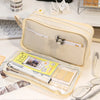 A beige transparent pencil pouch with a zipper and several pencils and paper items is displayed on a white surface.