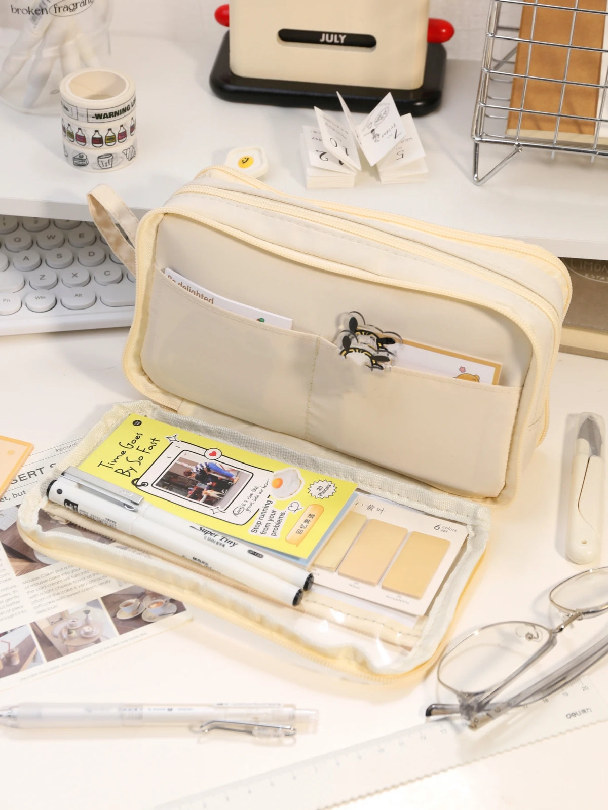 A beige transparent pencil pouch with a zipper and several pencils and paper items is displayed on a white surface.