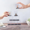 A hand is placing a miniature figure into a clear dustproof display case for collectibles.