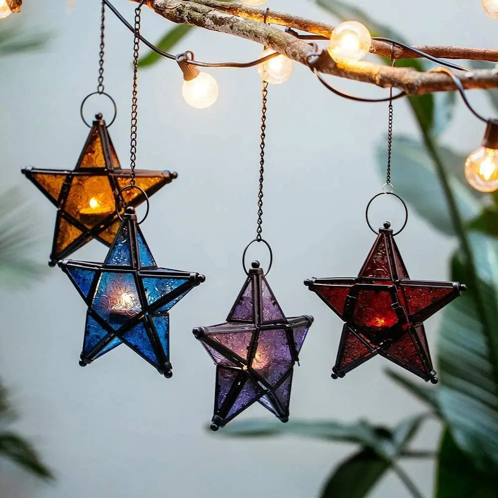 Forged iron star hanging candlestick with a dark blue and purple iridescent finish, suspended from a branch.