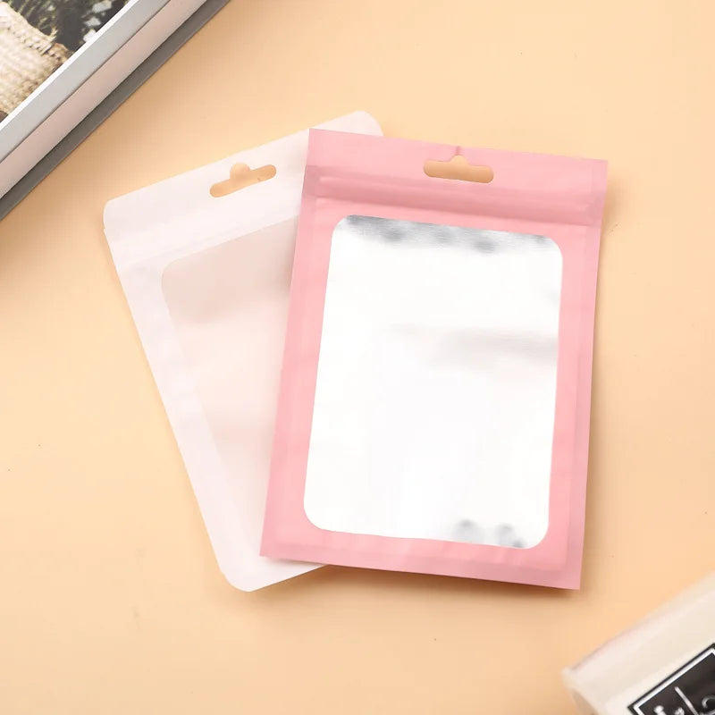 A pink jewelry display pouch with a reflective insert is shown next to a white pouch on a light background.