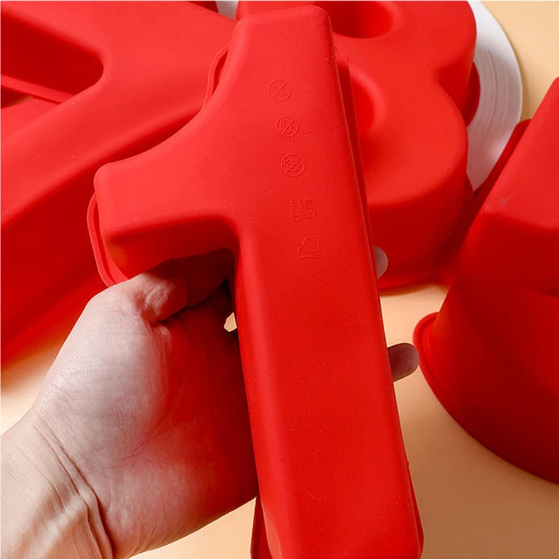 A hand holds a red silicone number cake mold, showing the texture and shape of the mold.