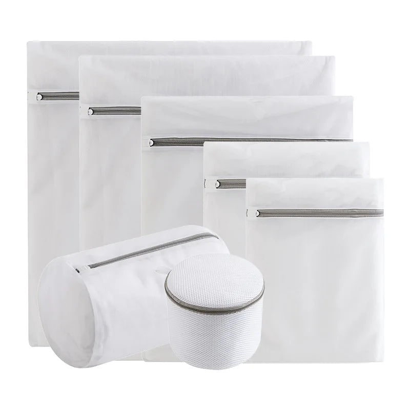 A stack of four white fine mesh laundry bags for delicate clothing, some closed and one open.