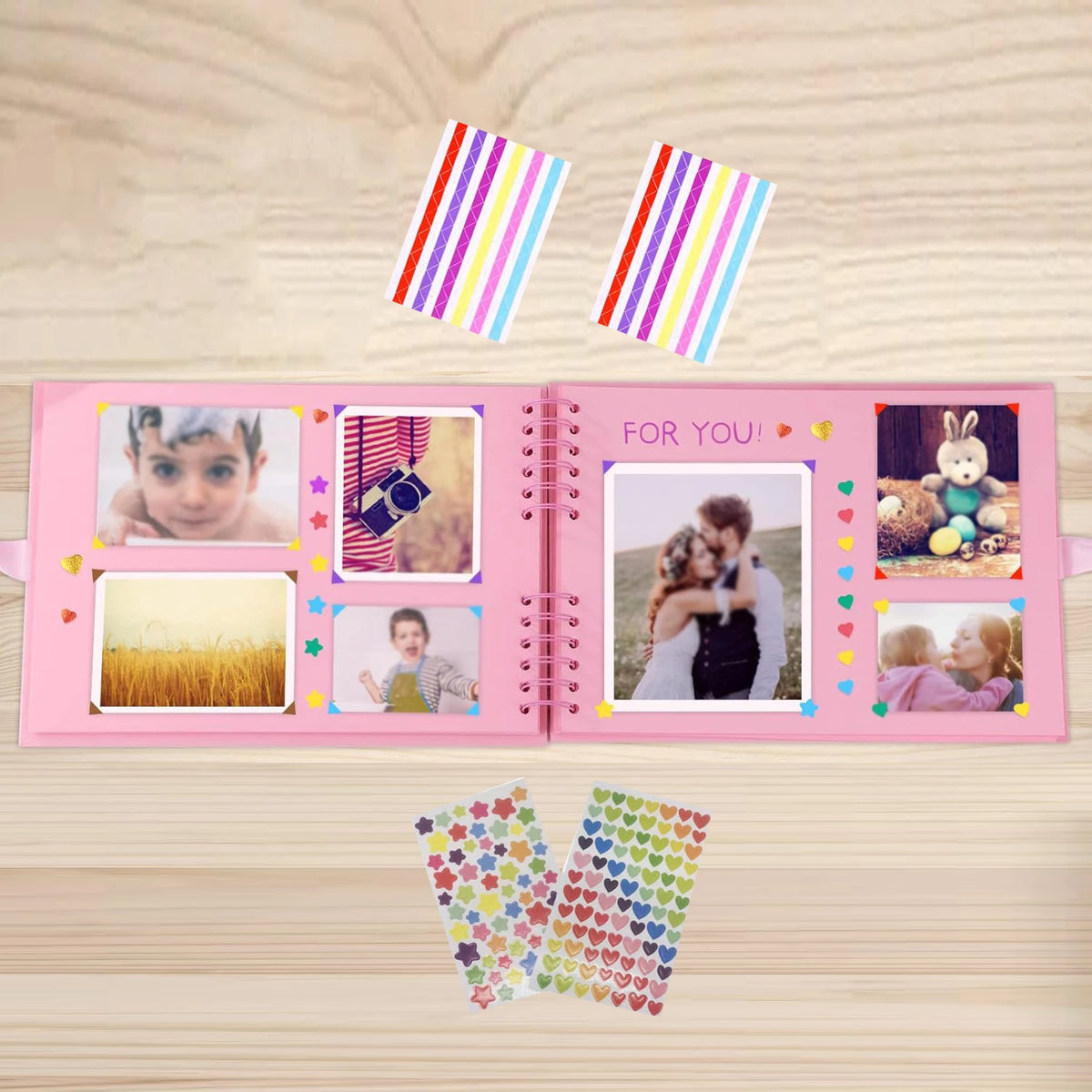 Álbum de scrapbooking rosa con páginas estampadas coloridas y pegatinas decorativas sobre una superficie de madera.