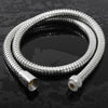 A coiled flexible stainless steel shower hose lying on a dark, reflective surface.