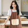 A young woman models a brown striped kitchen apron over a white t-shirt in a bright indoor setting.