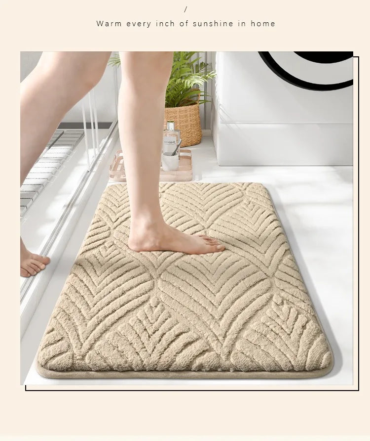A beige plush non-slip bathroom rug is shown on a white floor next to a bathtub.