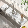 Moderne Küchenspüle mit Edelstahl-Wasserhahn und Marmortrockenmatte mit Holzutensilien.
