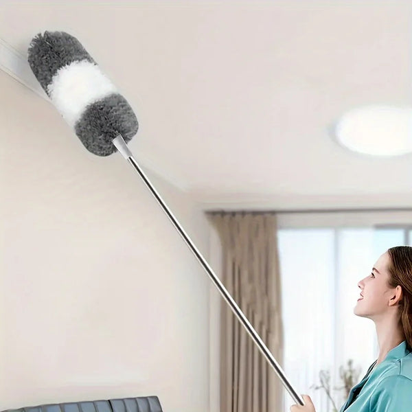 An extra-long retractable duster with a fluffy black and white head is shown extending from a wall in a bright room.