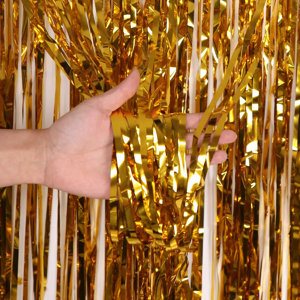 Eine Hand greift durch einen Vorhang aus metallischem Gold- und Weiß-Tinselfolienrand.